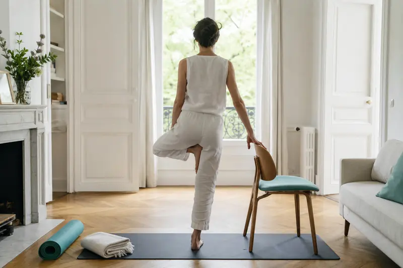 Débutant pratiquant le yoga doux avec une chaise dans un salon lumineux