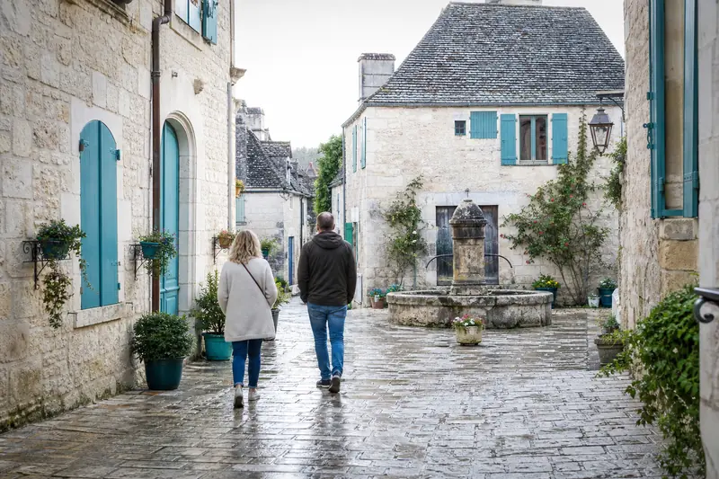 Visiteurs marchant dans les ruelles pavées d’un village pittoresque français.