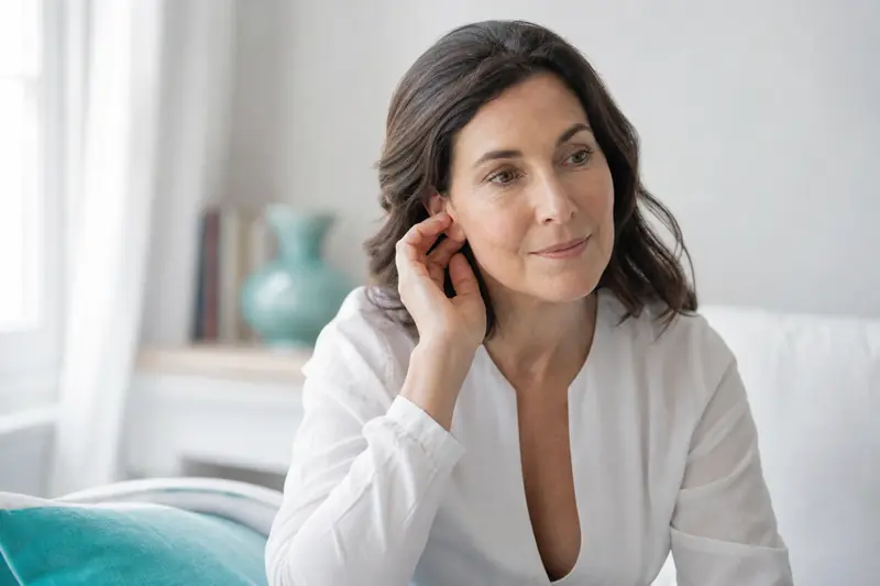 Personne se touchant l'oreille avec une main dans un environnement calme