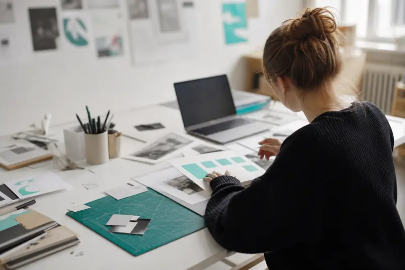 Étudiante préparant un projet de BTS design graphique sur ordinateur et papier.