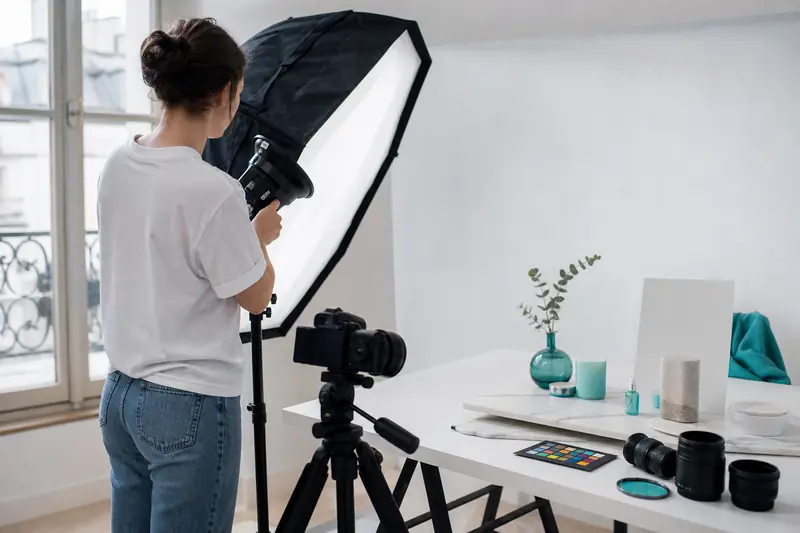 Étudiante en BTS photographie réglant un éclairage de studio pour une nature morte.