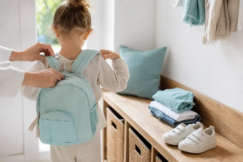Enfant portant un cartable maternelle léger et ajusté dans une entrée lumineuse