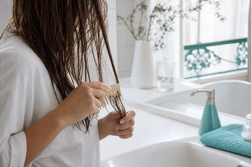 Démêlage doux de cheveux fragiles après lavage dans une salle de bains lumineuse