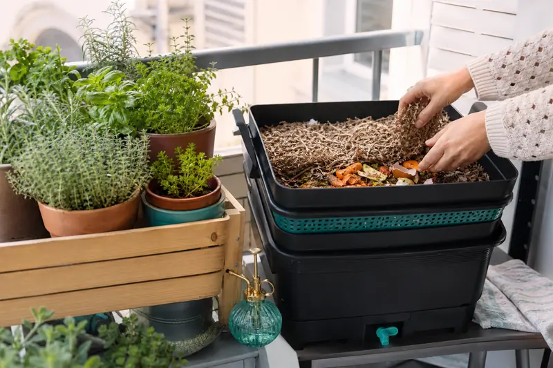 Composteur d’intérieur à plateaux près de plantes sur un balcon urbain