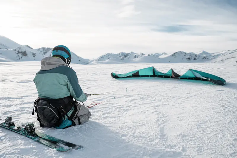 Débutant préparant son snowkite sur un plateau enneigé et dégagé.