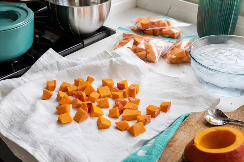 Dés de potimarron préparés pour la congélation sur un linge de cuisine