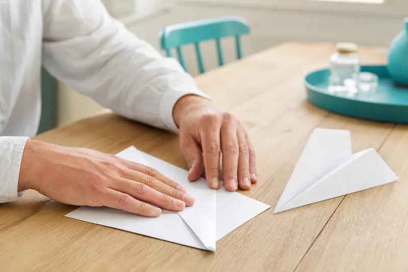 Pliage d’un avion en papier sur une table lumineuse