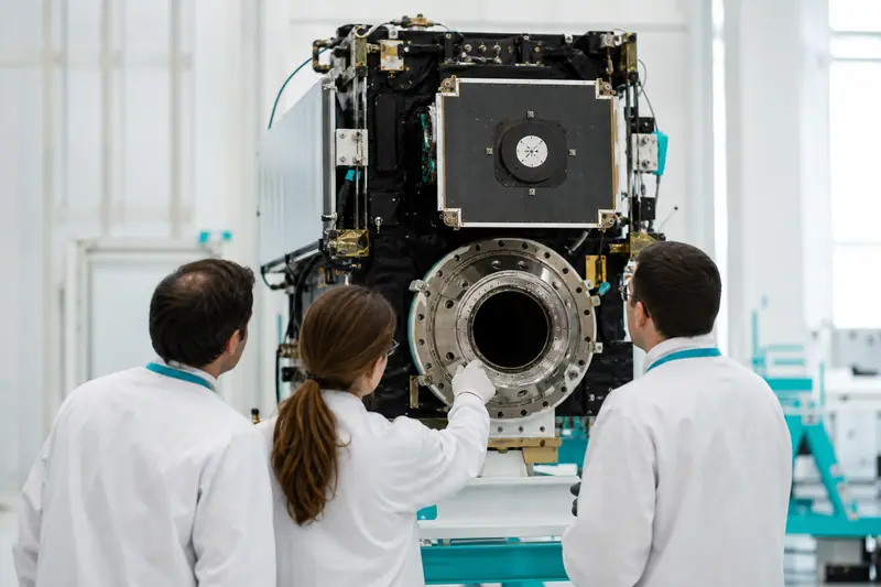 Ingénieurs inspectant un module de transport spatial dans une salle d’intégration aérospatiale.