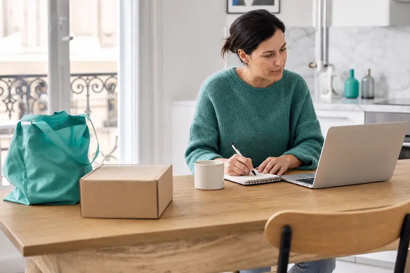 Une consommatrice compare des achats en ligne et son budget sur ordinateur portable.