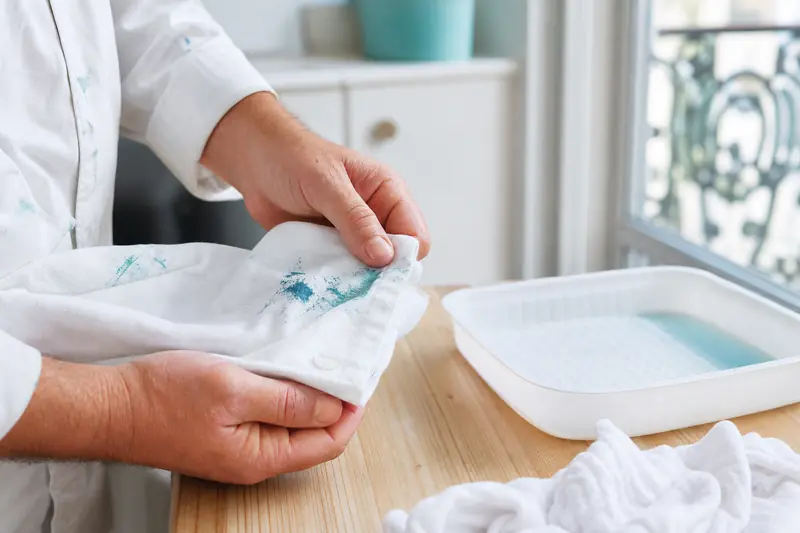 Détachage d’une tache de peinture fraîche sur une manche de vêtement blanc