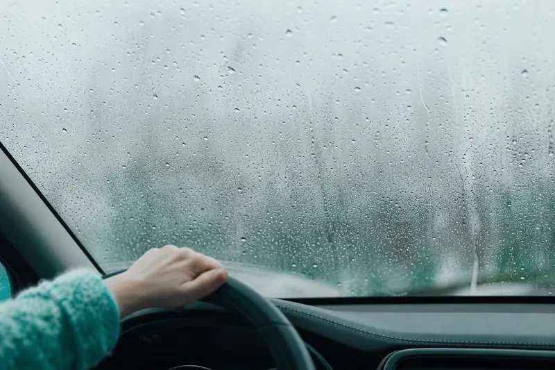 Habitacle de voiture humide avec vitre embuée sous la pluie