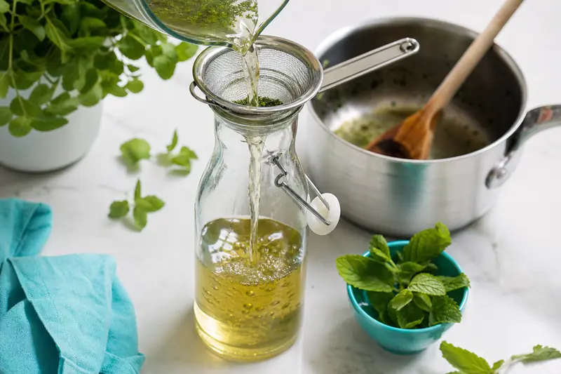 Filtrage d’un sirop de menthe maison dans une bouteille en verre.