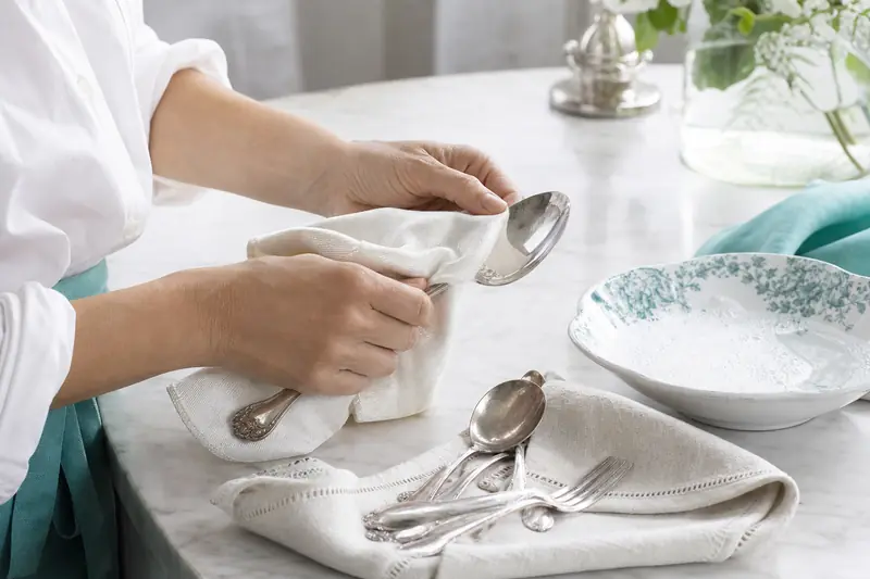 Nettoyage d’une cuillère en argent avec un chiffon doux sur une table.
