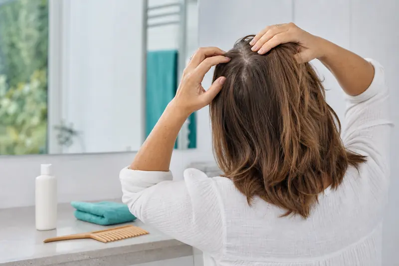 Femme examinant sa raie pour prévenir la chute des cheveux à 40 ans