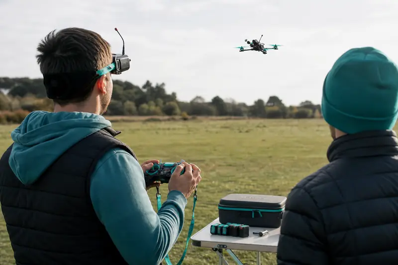 Télépilote équipé de lunettes FPV réalisant un vol en immersion avec observateur