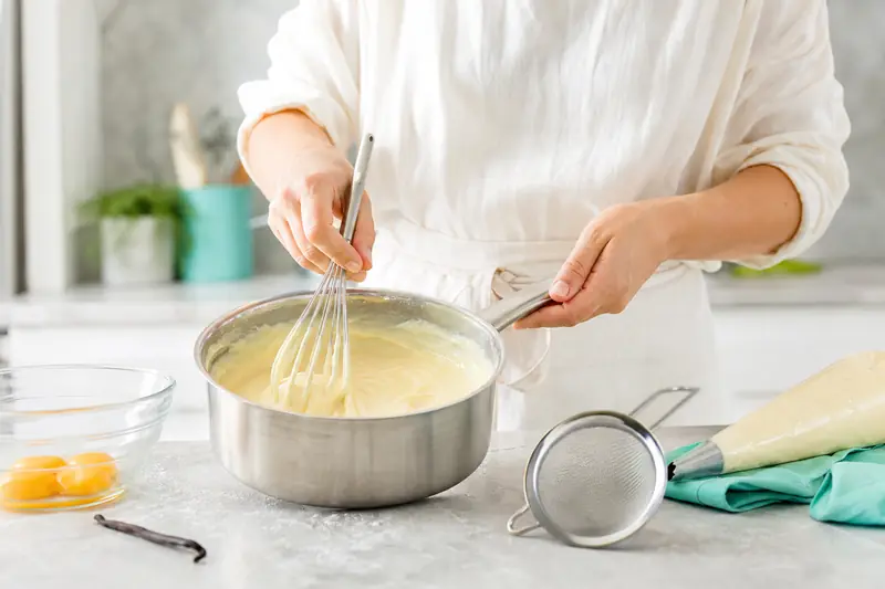 Crème pâtissière à la vanille fouettée dans une casserole en cuisine.