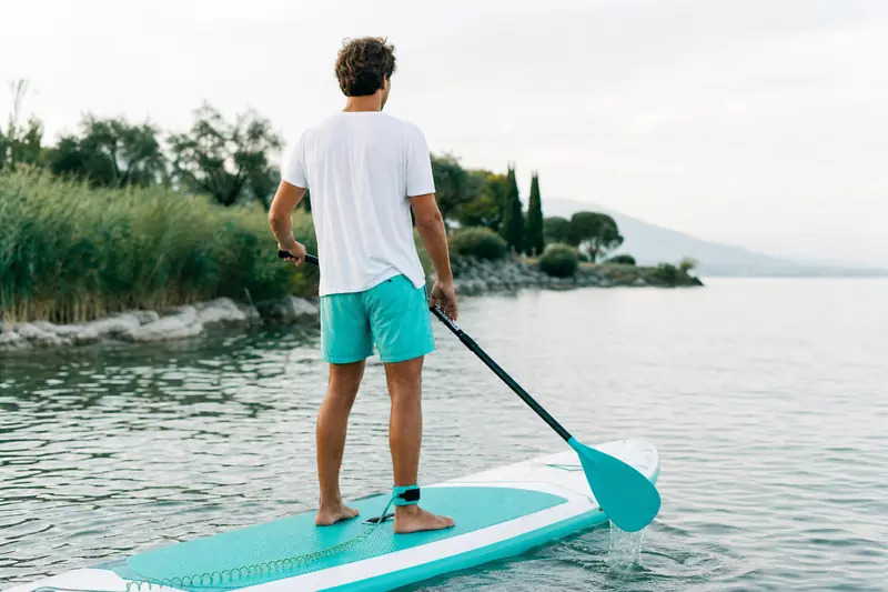 Débutant en yolo boarding debout sur un stand-up paddle sur lac calme