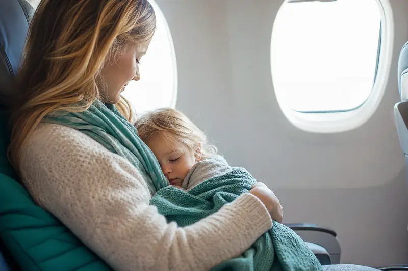 Jeune enfant endormi dans un avion contre un hublot éclairé de lumière douce
