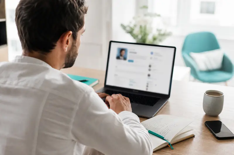 Professionnel optimisant son profil LinkedIn sur un ordinateur portable lumineux.