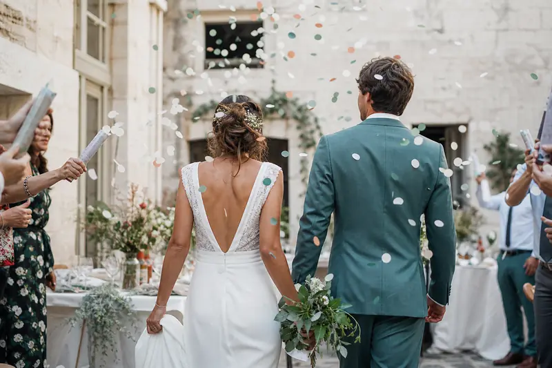 Mariés célébrant leur mariage sous un nuage de confettis pastel