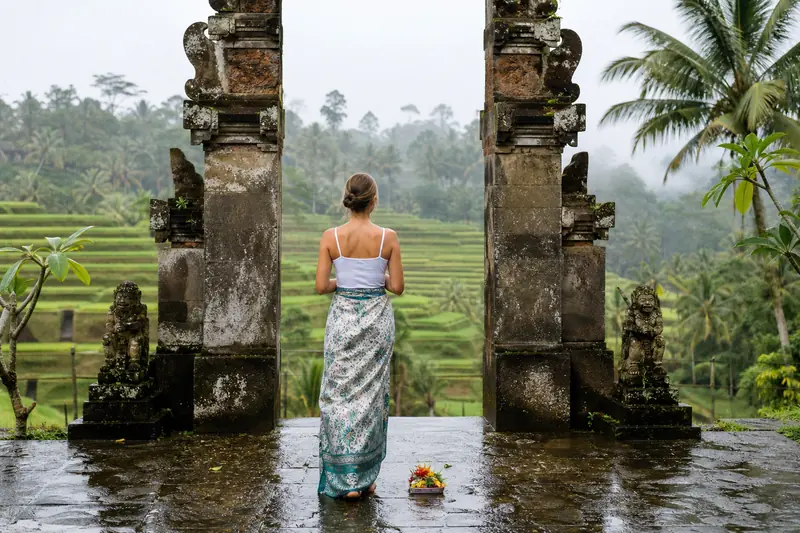 Voyageuse devant un temple balinais entouré de rizières verdoyantes à Bali.