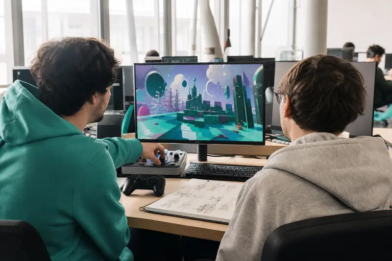 Étudiants en formation jeux vidéo travaillant sur un prototype dans un studio école.