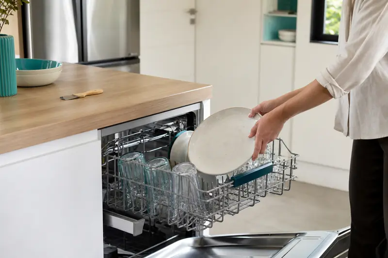 Chargement soigné d’un lave-vaisselle écologique dans une cuisine lumineuse.