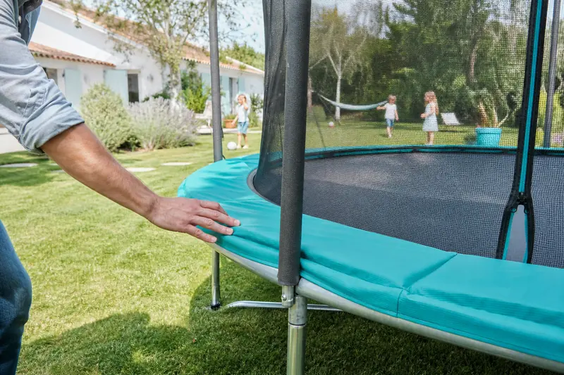 Trampoline de qualité avec filet et coussins de sécurité dans un jardin familial
