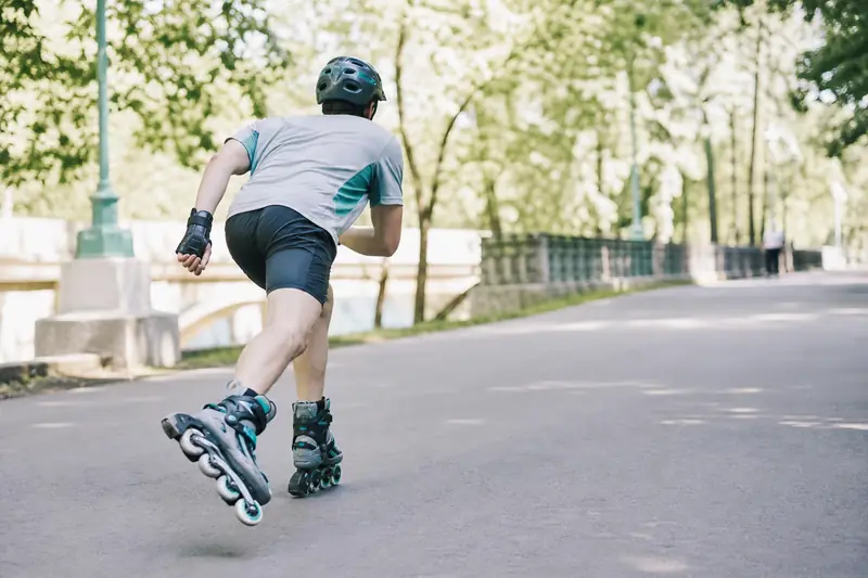 Pratiquante en roller travaillant la tonicité des jambes sur une piste lisse