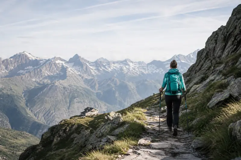 Randonneur sur un sentier alpin, face aux sommets d’une destination randonnée.