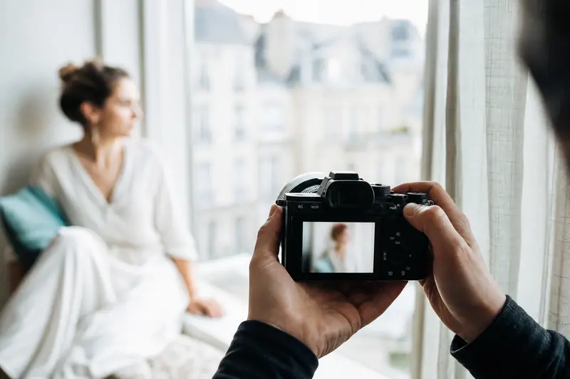 Photographe réglant la mise au point près d’une fenêtre pour une prise de vue nette