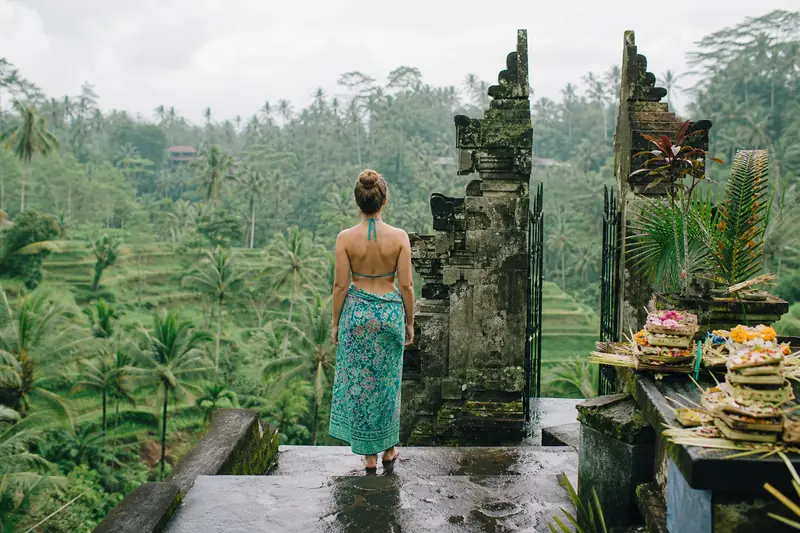 Voyageuse observant des rizières en terrasse à Bali depuis un sentier de pierre.
