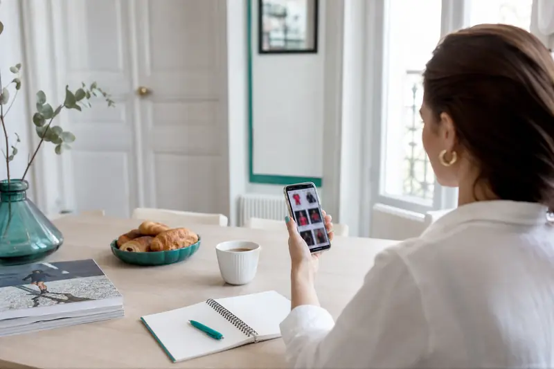 Consultation d’actualité people sur smartphone et magazines dans un salon lumineux