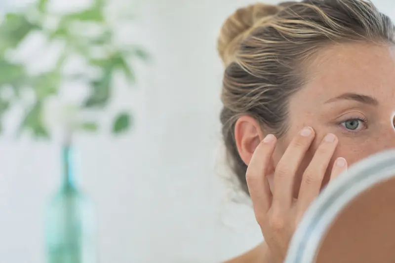 Personne se massant délicatement le contour de l'œil avec les doigts