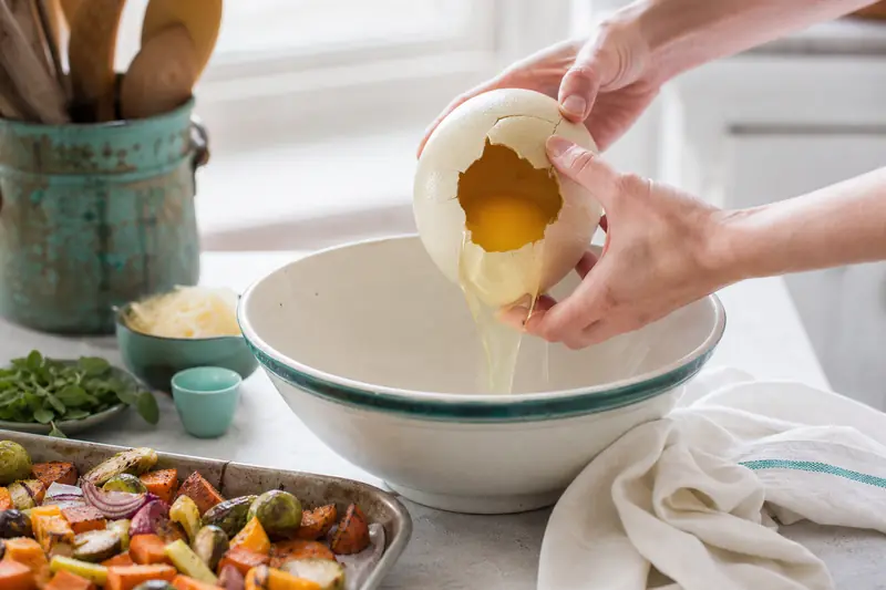 Œuf d’autruche ouvert pour une frittata aux légumes dans une cuisine familiale