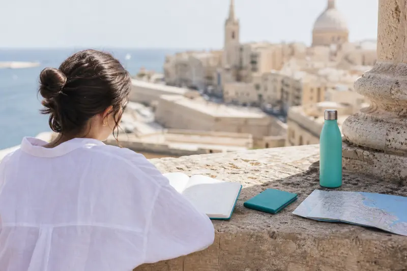 Voyageuse préparant un séjour linguistique à Malte sur une terrasse ensoleillée
