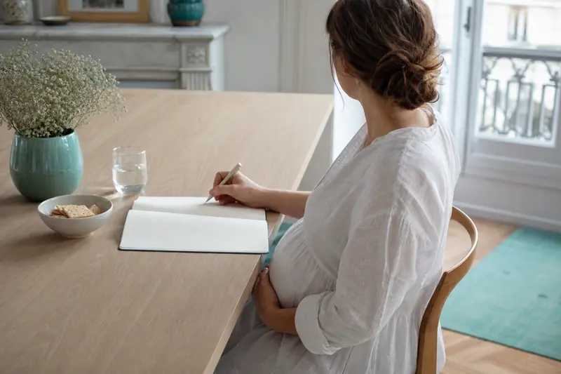 Femme enceinte notant ses symptômes de grossesse à une table lumineuse