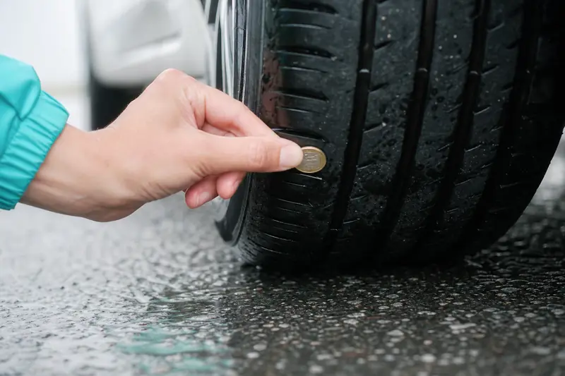 Gros plan sur la bande de roulement d'un pneu de voiture posé sur le bitume, lumière naturelle