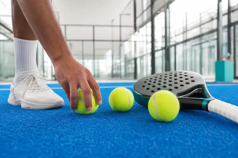 Comparatif de balles de padel neuves posées sur un court intérieur