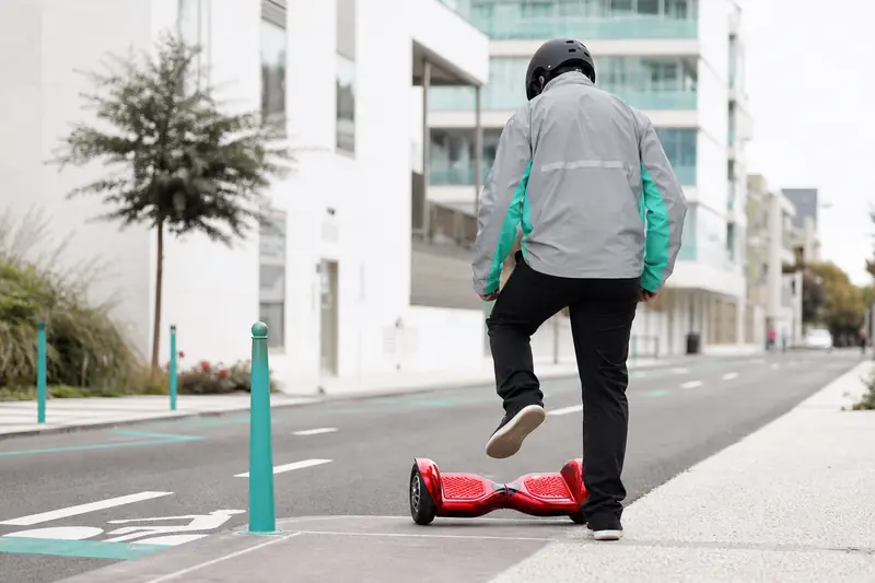 Hoverboard rouge près d’une piste cyclable urbaine avec casque et équipement réfléchissant