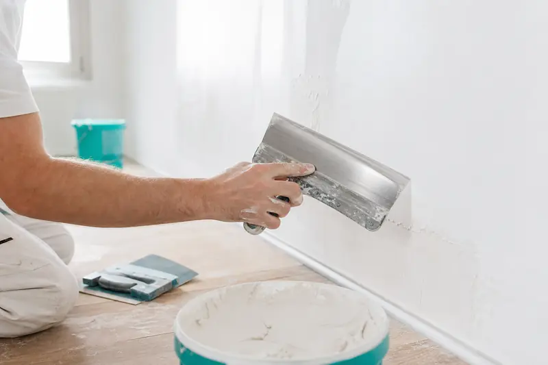 Application d’un enduit de finition sur un mur intérieur avec une lame large