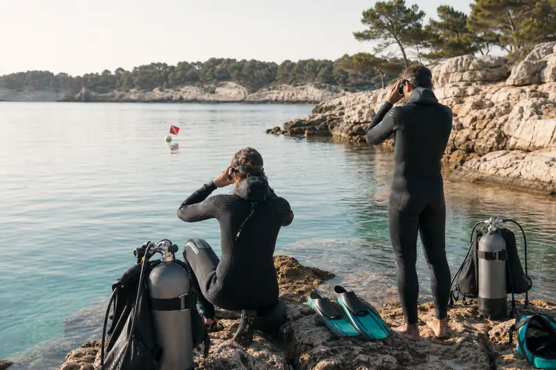 Deux plongeurs préparent une plongée matinale sur une côte méditerranéenne calme.