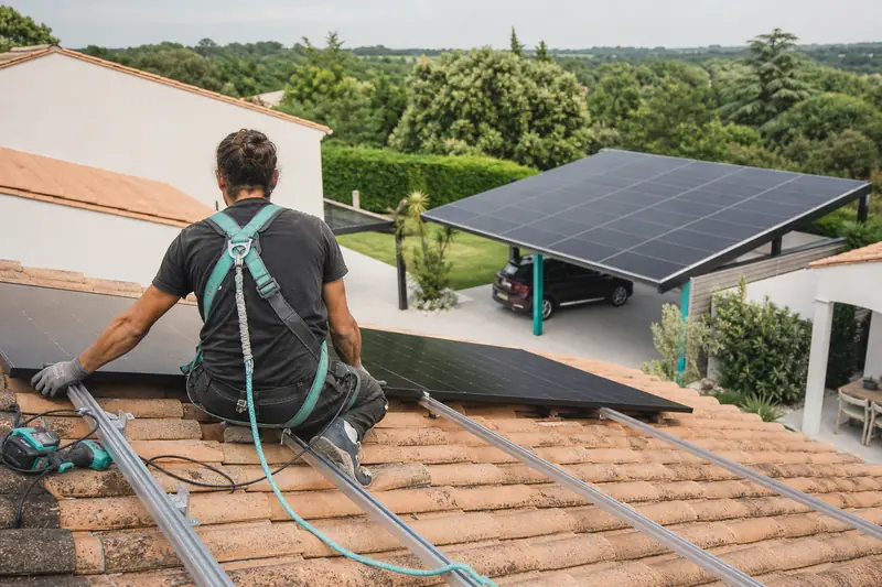 Installateur posant des panneaux solaires photovoltaïques sur une toiture de maison.