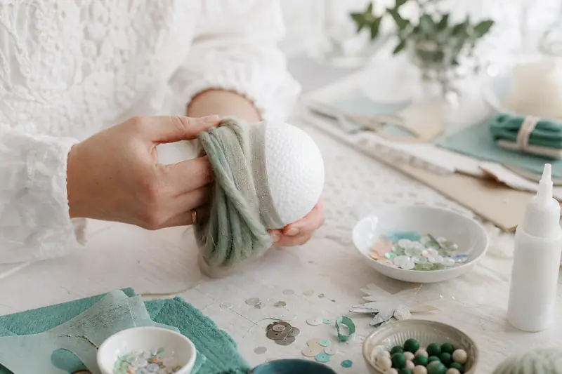 Boule de polystyrène habillée de laine et ruban sur une table créative