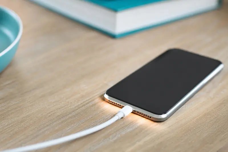 Smartphone posé sur une table en train de charger avec un câble branché