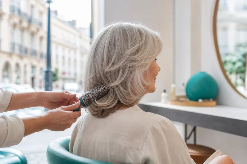 Coiffure mi-longue dégradée sur cheveux gris d’une femme de 70 ans