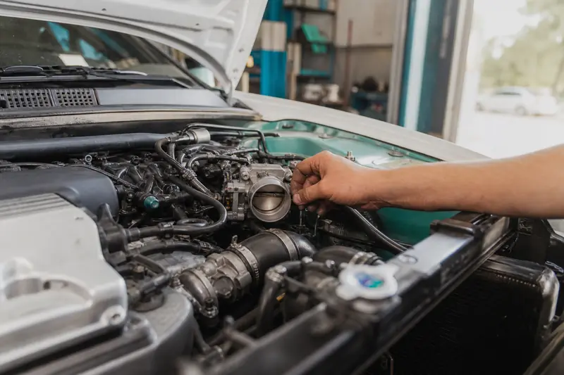 Mécanicien penché sous le capot ouvert d'une voiture pour vérifier le moteur au ralenti