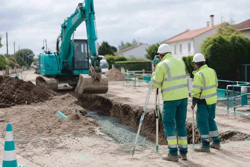Équipe de terrassement en travaux publics préparant une tranchée de réseau enterré.