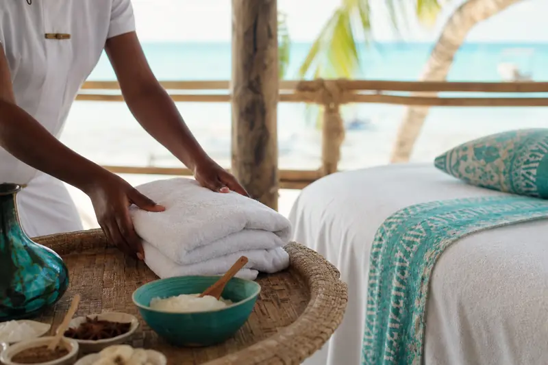 Espace spa à Zanzibar avec serviettes, huiles de massage et vue sur l’océan.
